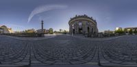 a fish eye view of a clock tower in an old town square and some buildings