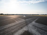 a sun shines through the clouds above an airfield runway and a tarmac with an airplane