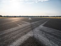 a sun shines through the clouds above an airfield runway and a tarmac with an airplane