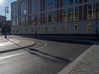 a street light next to an empty road in front of a building with a traffic light on top of it