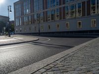 a street light next to an empty road in front of a building with a traffic light on top of it