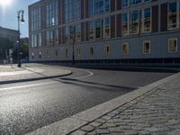 a street light next to an empty road in front of a building with a traffic light on top of it