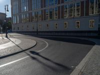 a street light next to an empty road in front of a building with a traffic light on top of it