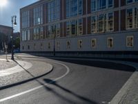 a street light next to an empty road in front of a building with a traffic light on top of it