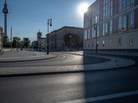 a street light next to an empty road in front of a building with a traffic light on top of it