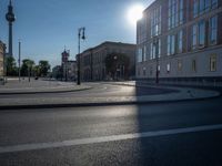 a street light next to an empty road in front of a building with a traffic light on top of it