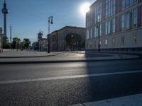 a street light next to an empty road in front of a building with a traffic light on top of it