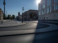 a street light next to an empty road in front of a building with a traffic light on top of it