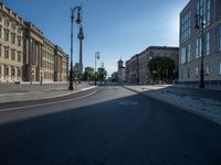 a street light next to an empty road in front of a building with a traffic light on top of it