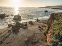 a grassy field by the shore and a cliff with rocks in the ocean in the background