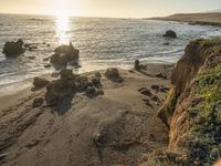 a grassy field by the shore and a cliff with rocks in the ocean in the background