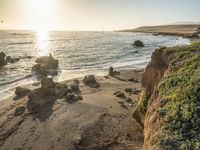 a grassy field by the shore and a cliff with rocks in the ocean in the background