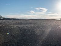 a person on a motorcycle stands in a rocky field as the sun rises behind them