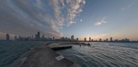 a photo of the city skyline of chicago from the ocean line at sunset, with a concrete jett in front of it