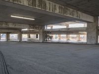 an empty parking garage with no cars on the side walk of it, with light at top