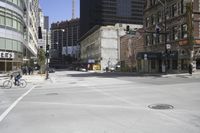 an empty street filled with tall buildings and people on bicycles and pedestrians walking around the intersection