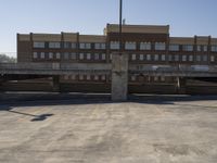 a building is under an overpass in an empty lot with a street light and parking lot signs