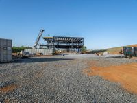 a picture of a building being built on a field near a forest in the background