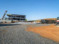 a picture of a building being built on a field near a forest in the background