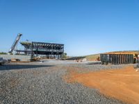 a picture of a building being built on a field near a forest in the background