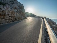 a road leading to a rocky outcropping with some trees in the distance