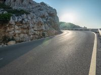 a road leading to a rocky outcropping with some trees in the distance