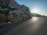 a road leading to a rocky outcropping with some trees in the distance