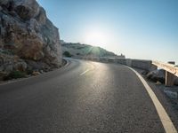 a road leading to a rocky outcropping with some trees in the distance