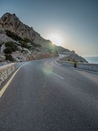 a man is riding on the road on the mountain top next to the ocean and cliff