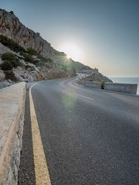 a man is riding on the road on the mountain top next to the ocean and cliff