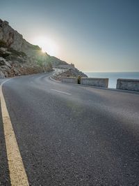 a man is riding on the road on the mountain top next to the ocean and cliff