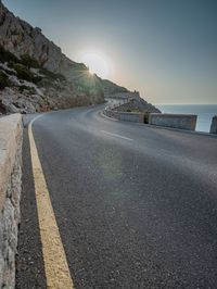 a man is riding on the road on the mountain top next to the ocean and cliff