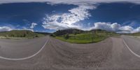 a road curves in a very cloudy sky near mountains with snow on it and a blue sky