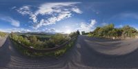 a road curves in a very cloudy sky near mountains with snow on it and a blue sky