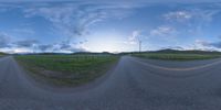 a road curves in a very cloudy sky near mountains with snow on it and a blue sky