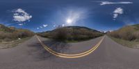 a road curves in a very cloudy sky near mountains with snow on it and a blue sky