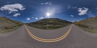 a road curves in a very cloudy sky near mountains with snow on it and a blue sky