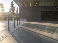 large cement sidewalk and metal poles in front of a building with a bright light coming through the window