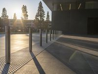 large cement sidewalk and metal poles in front of a building with a bright light coming through the window