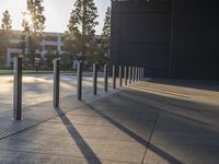 large cement sidewalk and metal poles in front of a building with a bright light coming through the window