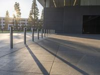 large cement sidewalk and metal poles in front of a building with a bright light coming through the window