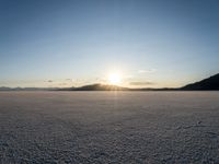 the sun is shining brightly on the ground in a vast plain area with snow and rocks