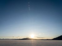 the sun is shining brightly on the ground in a vast plain area with snow and rocks