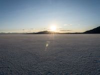 the sun is shining brightly on the ground in a vast plain area with snow and rocks