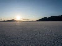 the sun is shining brightly on the ground in a vast plain area with snow and rocks