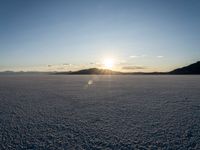 the sun is shining brightly on the ground in a vast plain area with snow and rocks