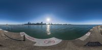 a fish eye view from an angle of the water and city skyline in the distance