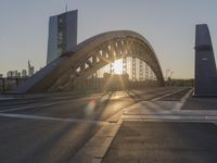 a large arch bridge spanning the width of an urban city street at sunset on a clear day