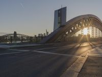 a large arch bridge spanning the width of an urban city street at sunset on a clear day