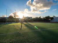 a football field with sunlight going down on it and many grass on the field that are very green